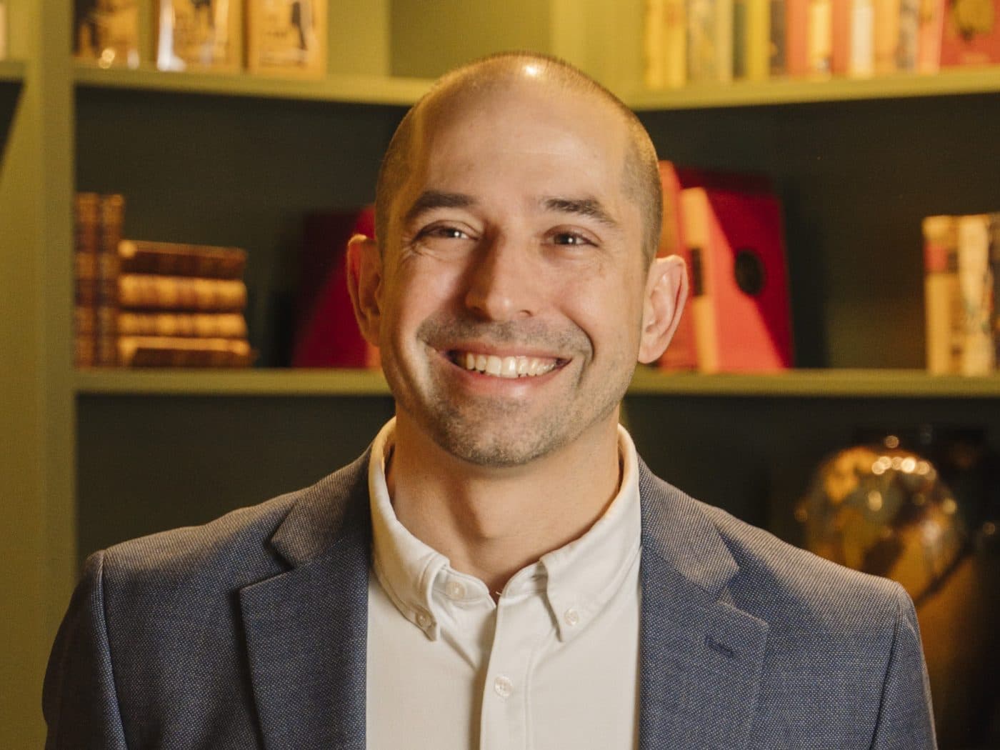 Dave Knox, smiling, in a library with green bookshelves